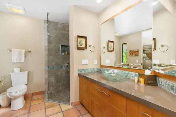 a spacious bathroom with a granite countertop sink a toilet a mirror and shower
