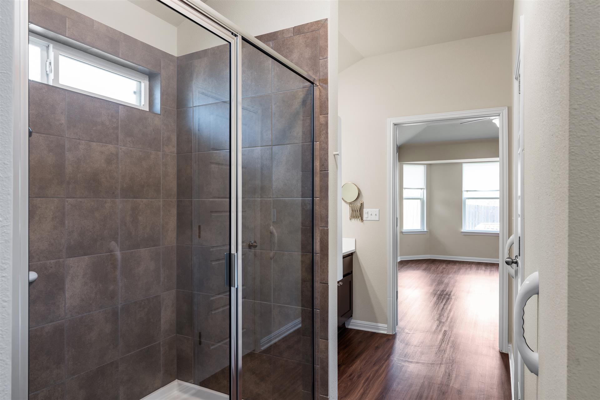 16512 Enamorado Road Manor, TX 78653 - Photo 27 of 31 A spacious shower with modern tilework and an adjacent vanity create a functional and stylish primary bathroom.