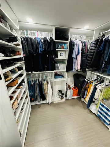 a view of walk in closet with clothes and shoes