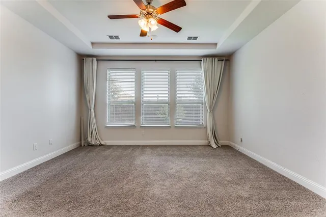 an empty room with windows and chandelier fan