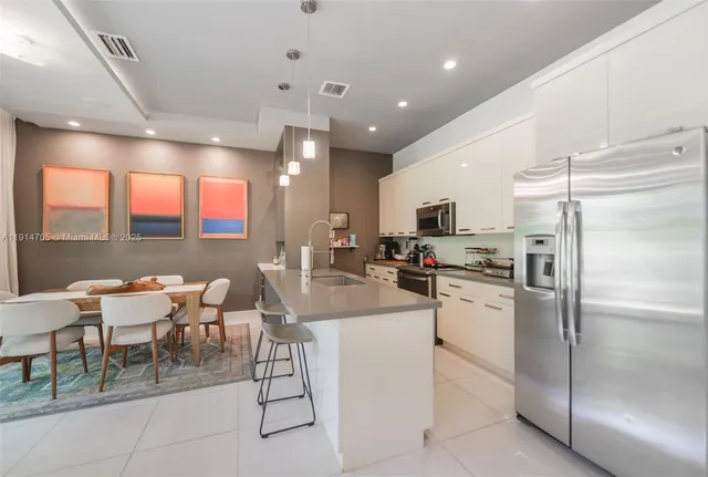 a kitchen with refrigerator and chairs