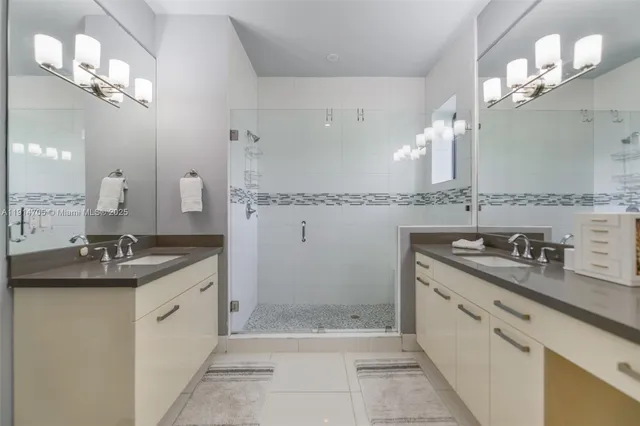 a bathroom with a sink double vanity granite tub shower and a mirror