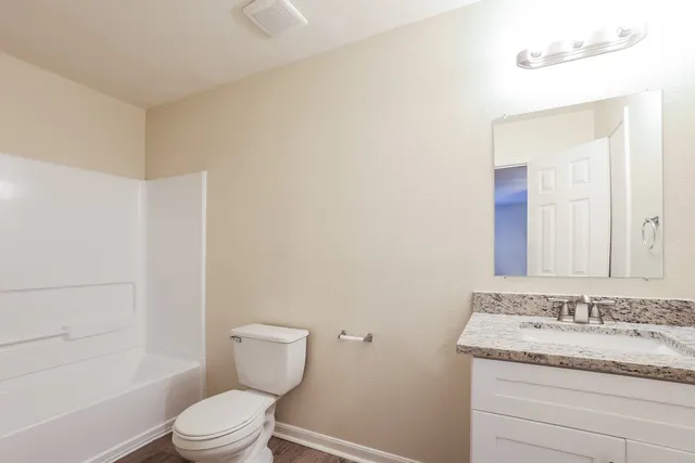 a bathroom with a granite countertop toilet a sink and a bathtub