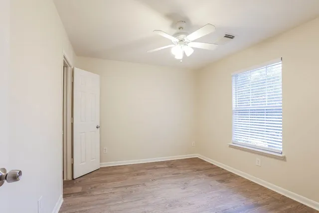 a view of an empty room with wooden floor and a window