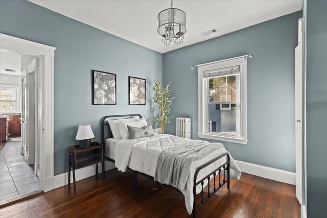 a bedroom with a bed wooden floor and window