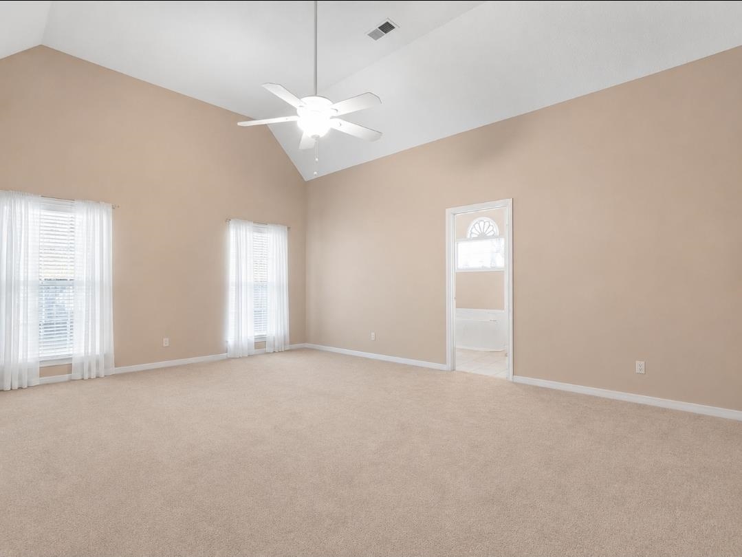 3779 Dancyville Road Stanton, TN 38069 - Photo 10 of 22 Spacious room featuring vaulted ceilings, a ceiling fan, two windows with blinds, a white door with decorative glass, and wall-to-wall carpeting