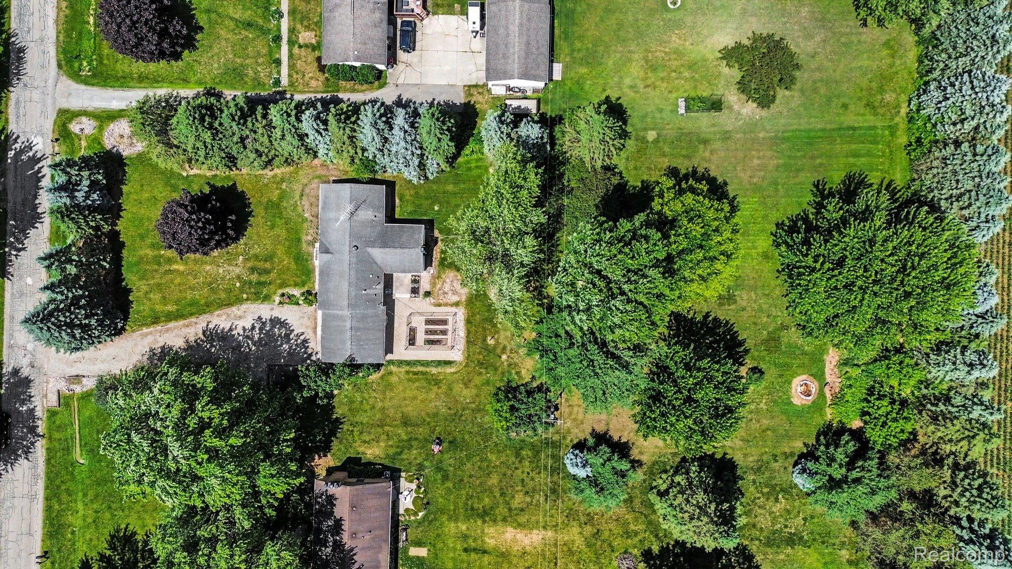74600 Nordman Court Romeo, MI 48065 - Photo 26 of 32 Extensive property featuring a residential structure with a gray shingle roof, surrounded by mature trees and a manicured lawn