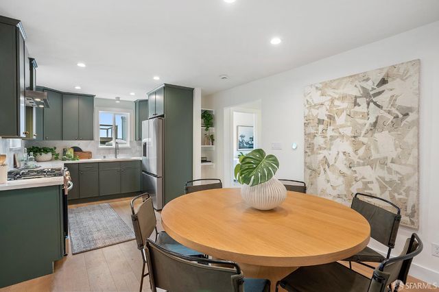 a kitchen with stainless steel appliances granite countertop a sink a stove a dining table and chairs