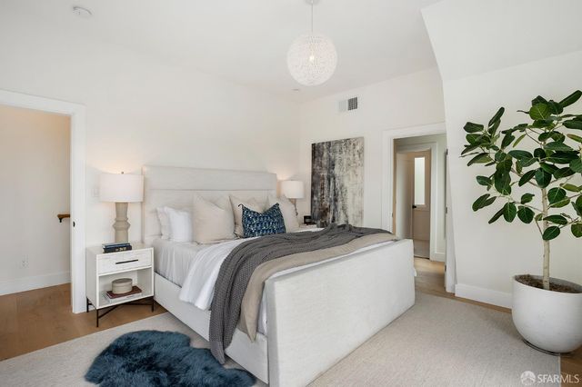 a spacious bedroom with a bed a couch and a potted plant