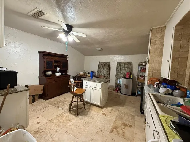 a work room with furniture a flat screen tv and kitchen view