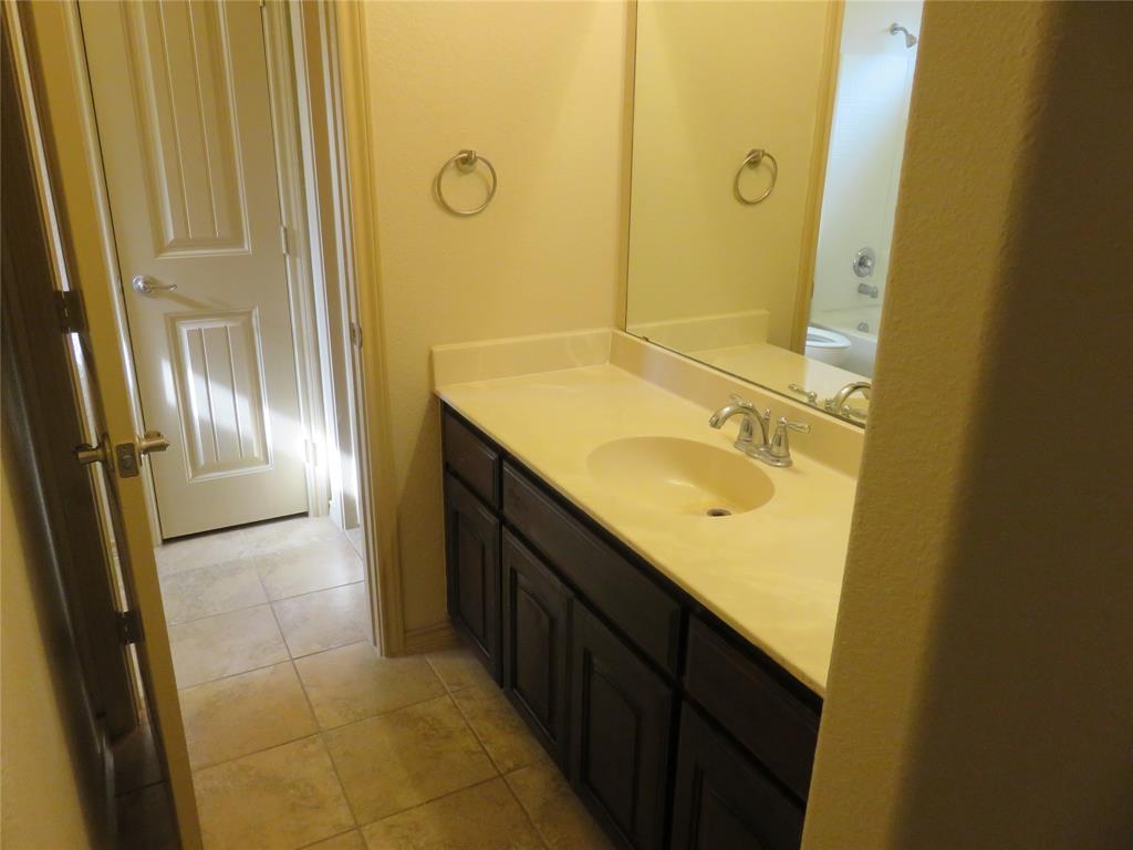 1122 Walter Stephenson Road Midlothian, TX 76065 - Photo 22 of 26 Bathroom vanity featuring a light-toned countertop with integrated sink, dark wood-finish cabinetry, and an expansive wall mirror