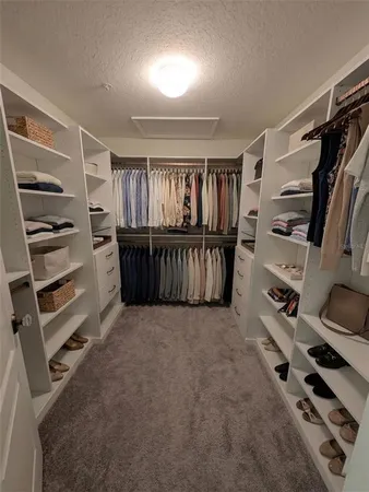 a view of walk in closet with clothes and shoes