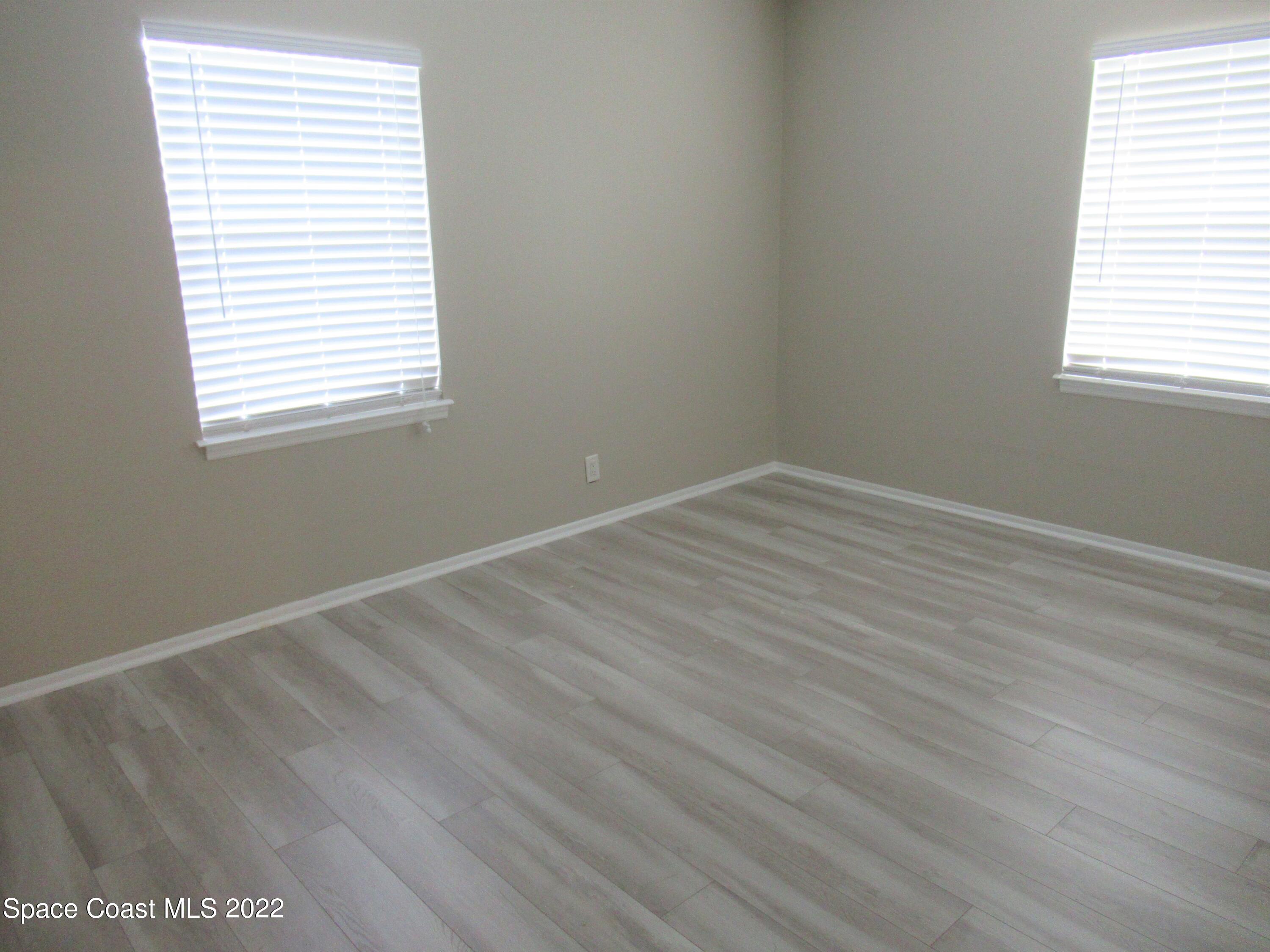 974 Bucknell Place Rockledge, FL 32955 - Photo 16 of 30 an empty room with wooden floor and windows