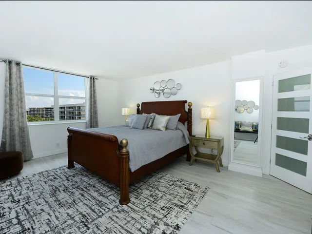 a bedroom with a bed a mirror on dresser and a wooden floor