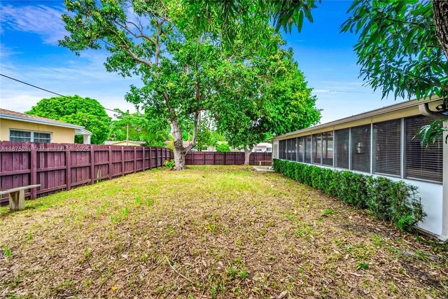 a view of a backyard with wooden fence and large trees