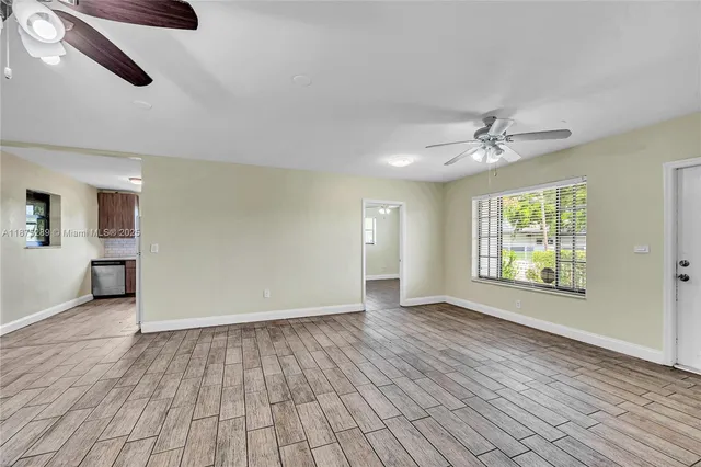 a view of an empty room with a window and wooden floor