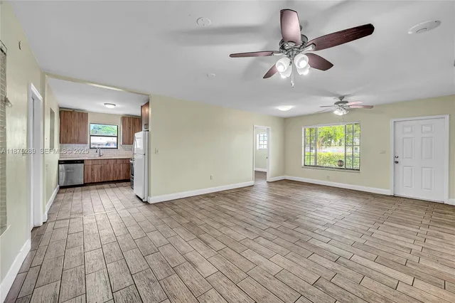 a view of an empty room with a window and wooden floor