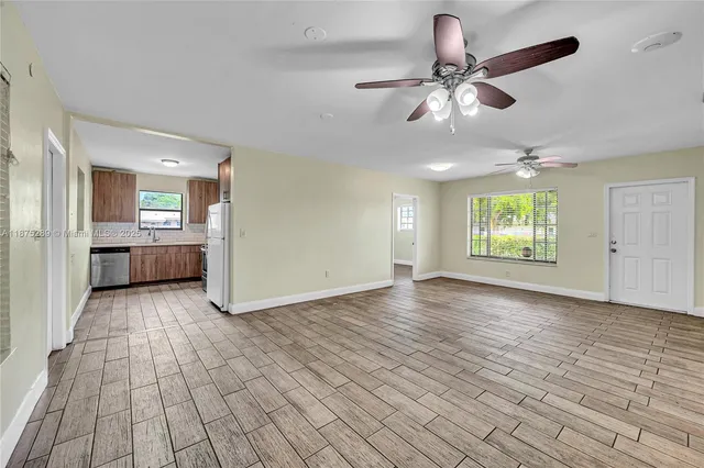 a view of an empty room with a window and wooden floor