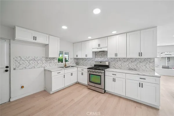 a kitchen with granite countertop white cabinets and white stainless steel appliances