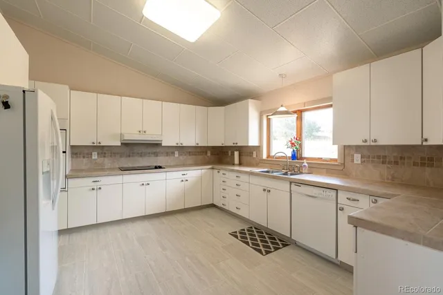 a kitchen with granite countertop white cabinets and refrigerator