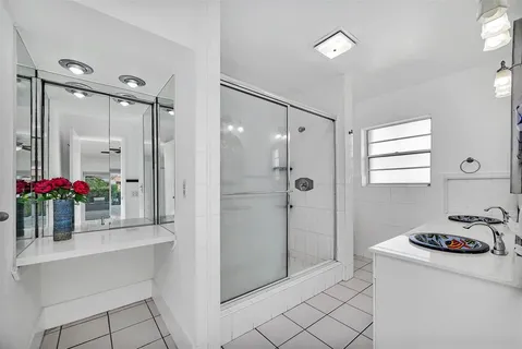 a bathroom with a sink vanity granite tub shower and a mirror
