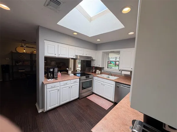 a kitchen with a sink cabinets stainless steel appliances and a window
