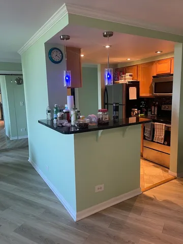 a room with kitchen island stainless steel appliances wooden floor and a living room view