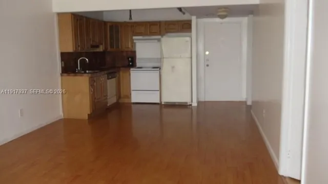 a view of a kitchen with a sink refrigerator and wooden floor