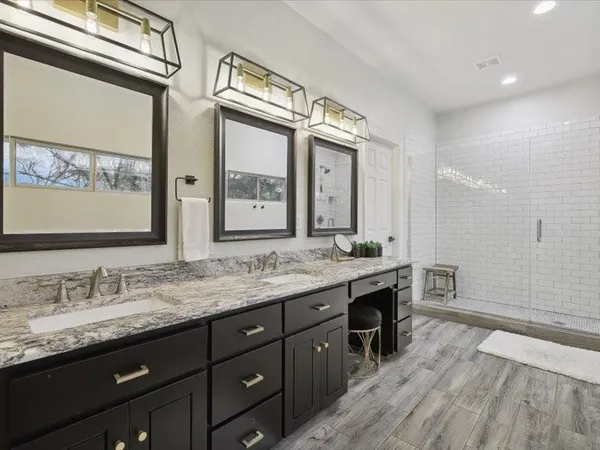 a spacious bathroom with a granite countertop double vanity sink a mirror and a shower