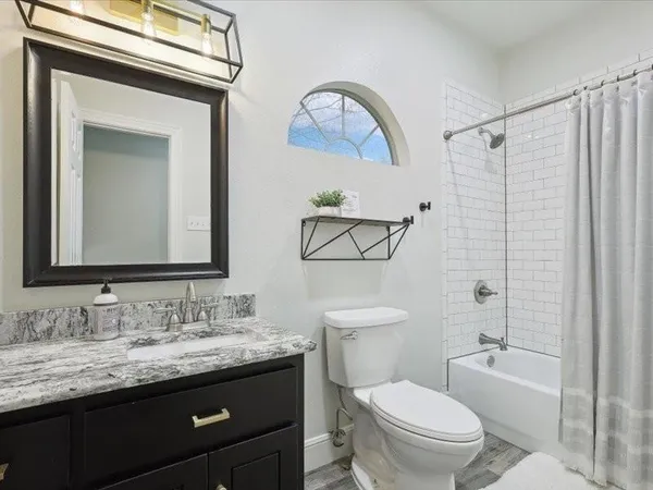 a bathroom with a granite countertop toilet a sink and a mirror