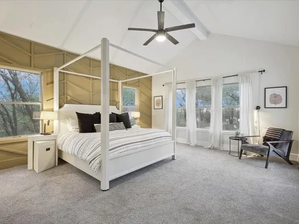 a bedroom with a bed a mirror and a flat tv screen on dresser