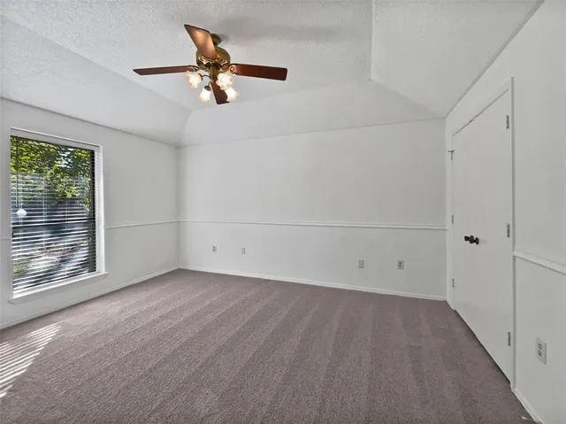 an empty room with a window and a ceiling fan