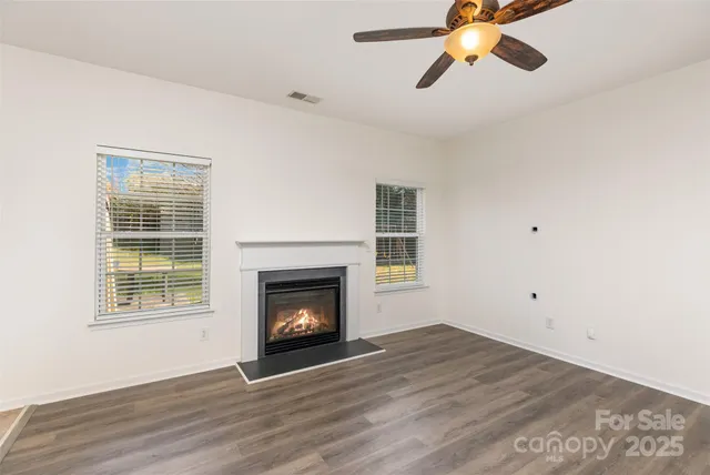 a view of empty room with wooden floor fireplace and a window