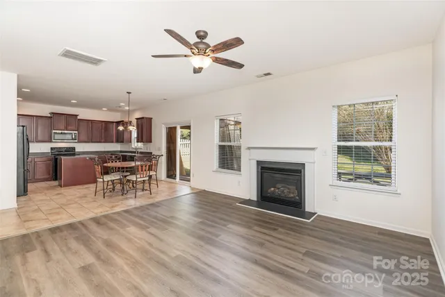 an empty room with wooden floor fireplace and windows
