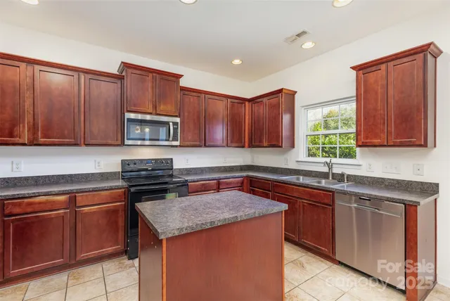 a kitchen with stainless steel appliances granite countertop wooden cabinets a sink and dishwasher a stove top oven with wooden floor