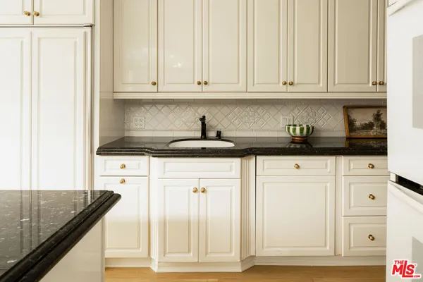 a kitchen with granite countertop white cabinets and sink