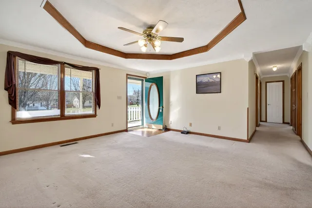 an empty room with chandelier fan and windows