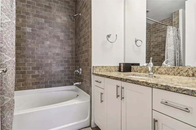 a bathroom with a granite countertop sink a mirror and a bathtub
