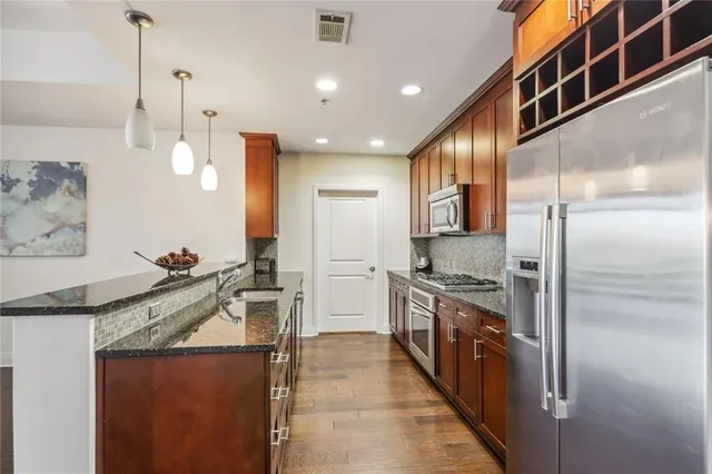 a kitchen with stainless steel appliances granite countertop a sink a stove and a refrigerator