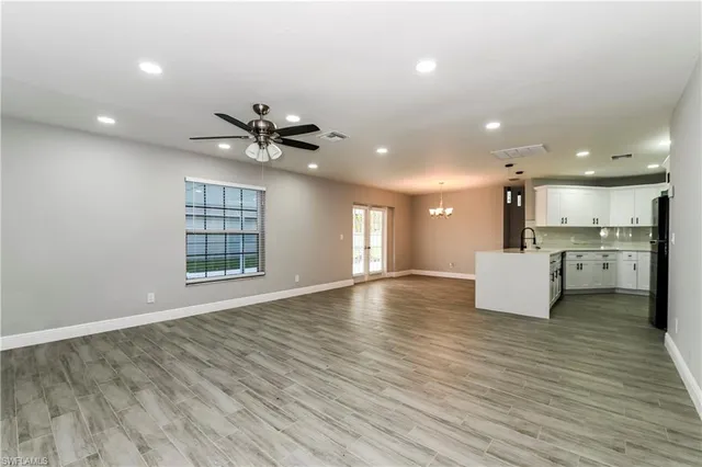 an empty room with wooden floor and a kitchen