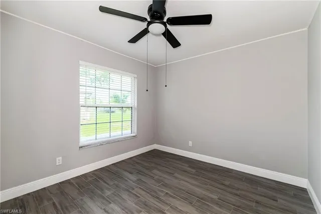 an empty room with wooden floor ceiling fan and windows