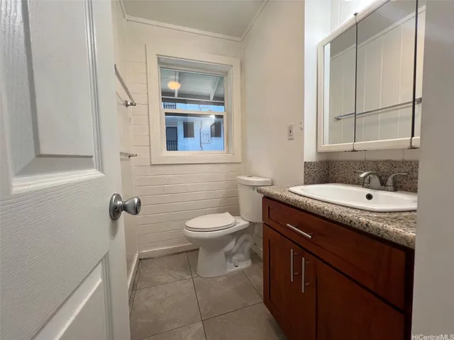 a bathroom with a granite countertop sink toilet and mirror
