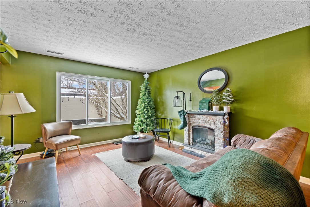 9956 Johnnycake Ridge Road, Unit F4 Painesville, OH 44077 - Photo 2 of 25 Living room with a fireplace, hardwood / wood-style floors, and a textured ceiling
