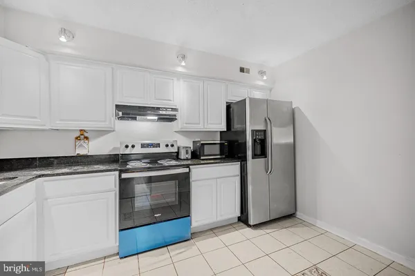 a kitchen with stainless steel appliances granite countertop a refrigerator and a stove top oven