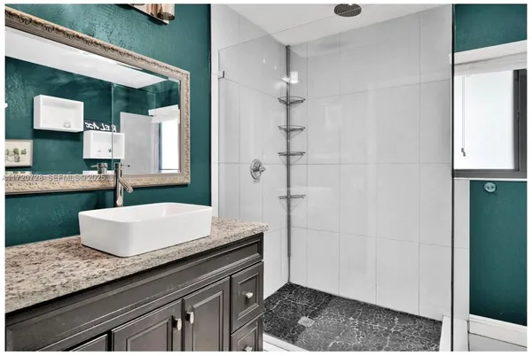 a bathroom with a granite countertop sink a mirror and shower