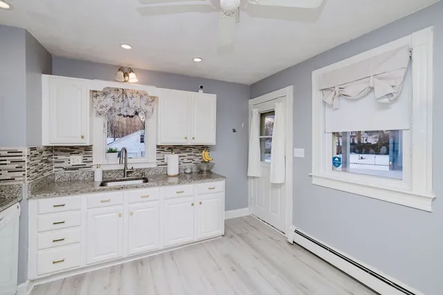 a large white kitchen with a sink a window and stainless steel appliances