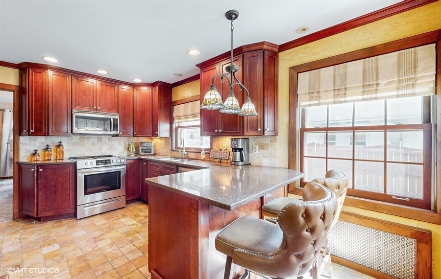633 Oakland Avenue Elgin, IL 60120 - Photo 11 of 35 a kitchen with stainless steel appliances granite countertop a stove top oven a sink dishwasher a dining table and chairs with wooden floor