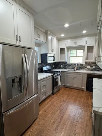 a kitchen with stainless steel appliances granite countertop a stove a sink dishwasher a refrigerator and a microwave