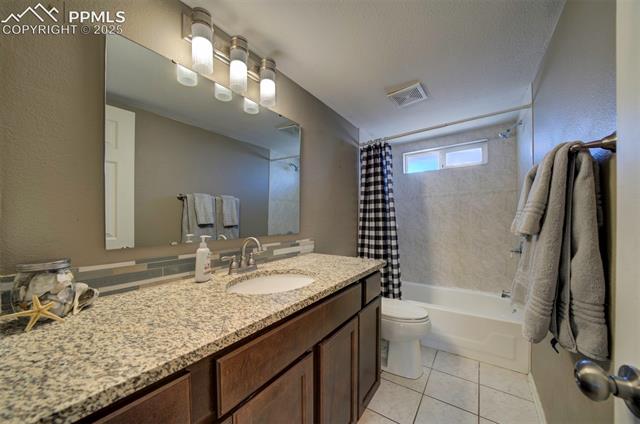 5860 Curtis Road Peyton, CO 80831 - Photo 21 of 28 Full bathroom with visible vents, shower / bath combo with shower curtain, toilet, tile patterned flooring, and vanity