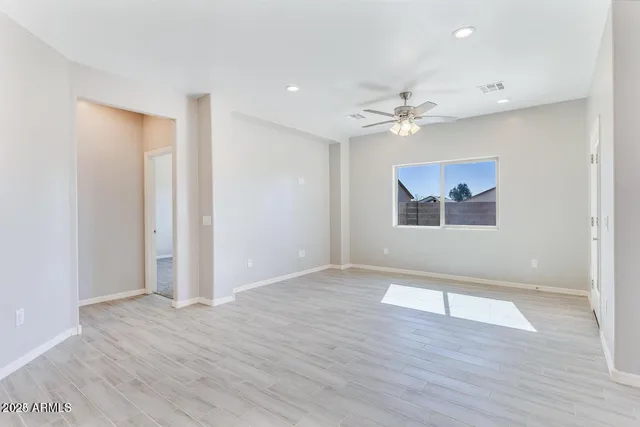 an empty room with wooden floor and ceiling fan